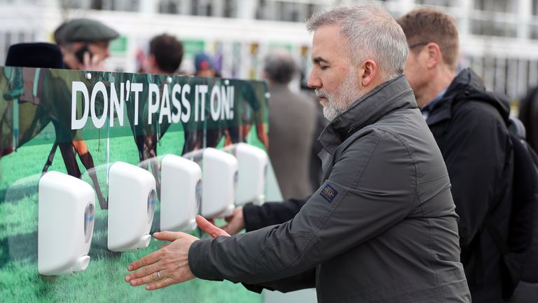 Les amateurs de course utilisent un désinfectant pour les mains pour garder leurs mains propres après une épidémie de coronavirus le premier jour du festival de Cheltenham à l'hippodrome de Cheltenham, Cheltenham.