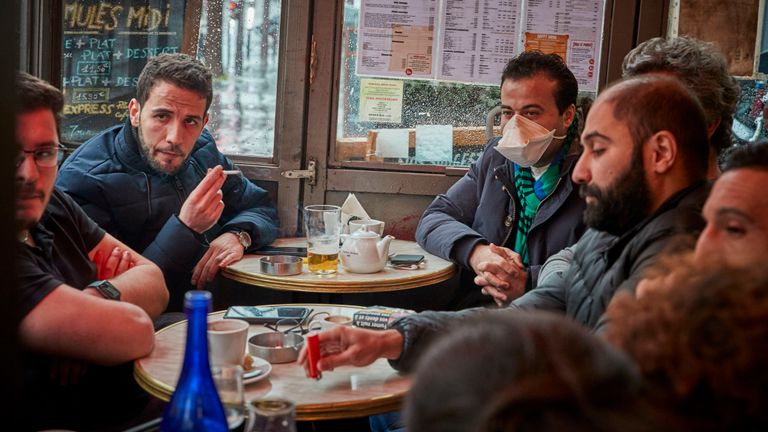 Un homme est assis dans un café parisien portant un masque facial alors que les rassemblements intérieurs de plus de 5 000 personnes ont été interdits