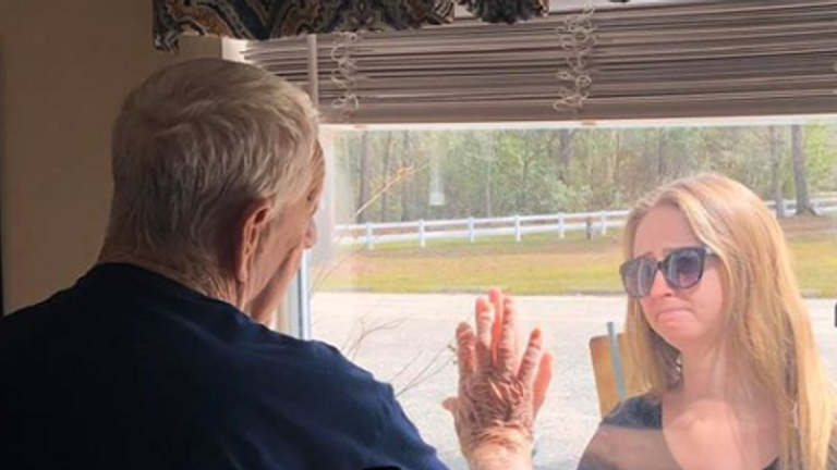 La paire a touché des mains de chaque côté de la fenêtre. Photo: Premier Living and Rehab Centre 
