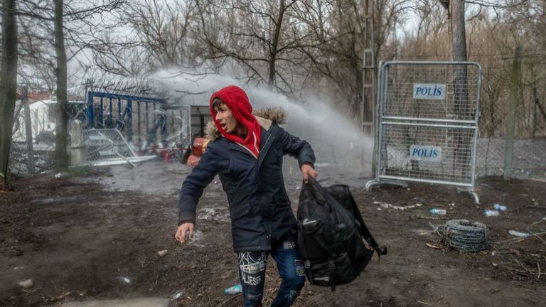Un migrant se tient devant des policiers grecs à la frontière de la zone tampon