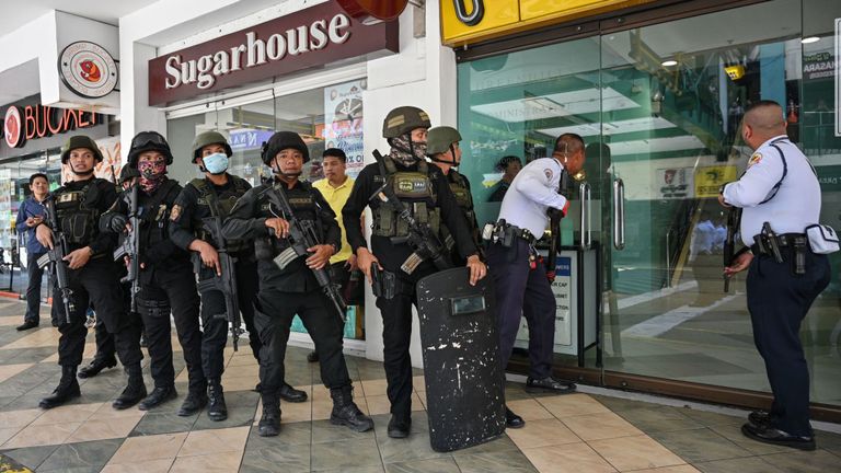 Des membres d'une équipe SWAT de la police se préparent à pénétrer dans un centre commercial après qu'une situation d'otage a été signalée dans la banlieue de Manille 