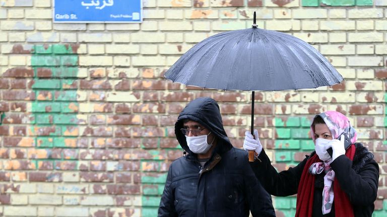 Les Iraniens portent des masques de protection pour éviter de contracter le coronavirus, alors qu'ils marchent dans la rue à Téhéran, Iran 25 février 2020