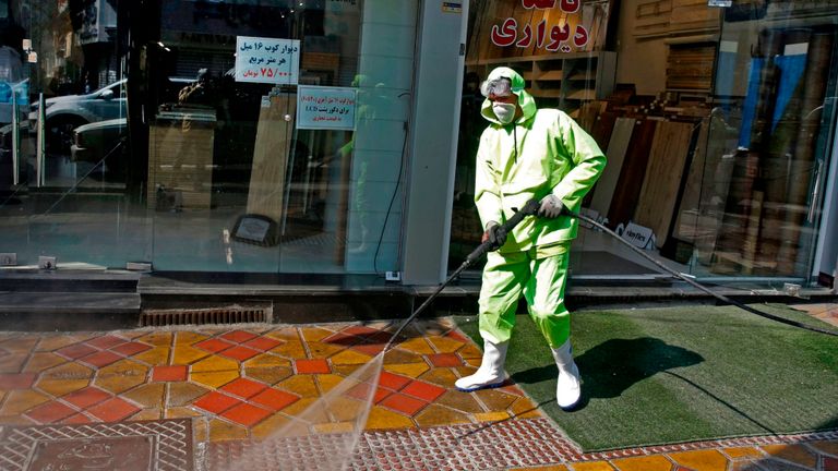 Des travailleurs iraniens désinfectent une rue de Téhéran
