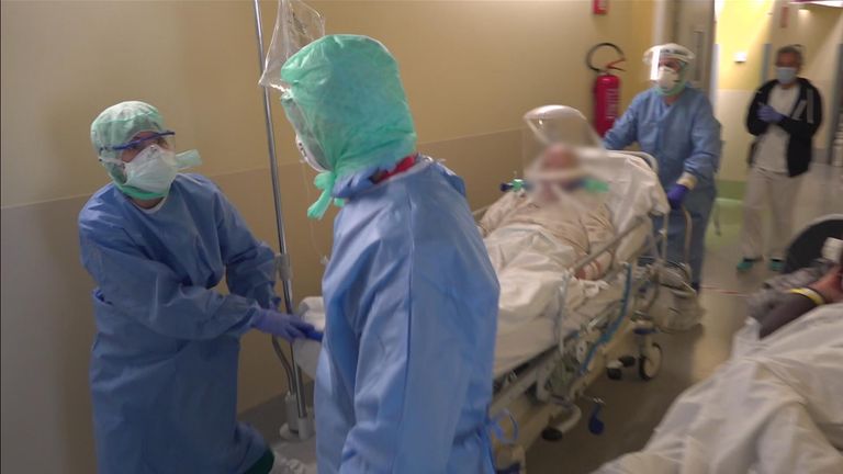 Le personnel de l'hôpital pousse une civière transportant un homme sur un respirateur mobile