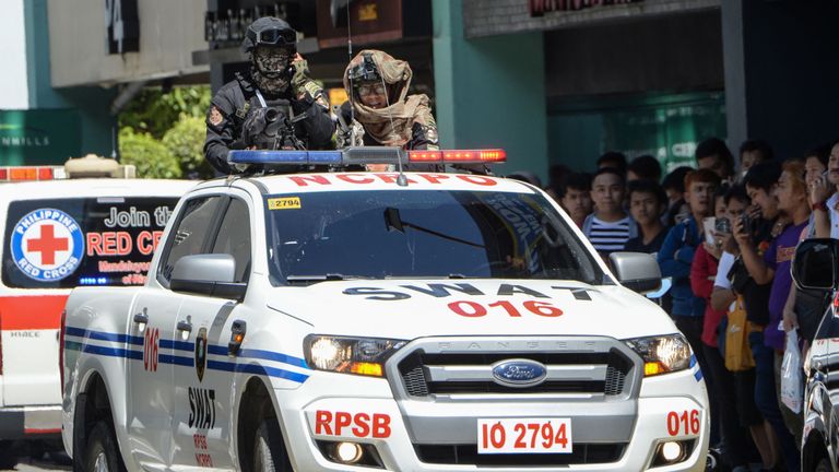 Des membres armés d'une équipe SWAT de la police se tiennent à l'arrière d'un camion près du centre commercial de Manille