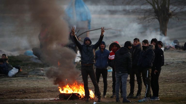 Les migrants se rassemblent autour d'un incendie en attendant de traverser le fleuve Evros pour atteindre la Grèce