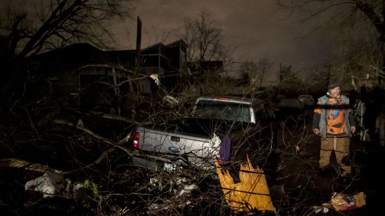 Un homme marche par une camionnette endommagée par la tempête sur la rue Underwood le 3 mars 2020 à Nashville, Tennessee