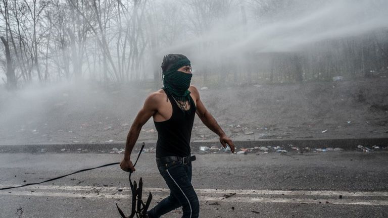 Un migrant affronte la police grecque à la frontière de la zone tampon, près de la porte de passage de Pazarkule à Edirne, Turquie