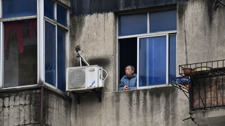 Un homme regarde par la fenêtre dans un complexe résidentiel à Wuhan