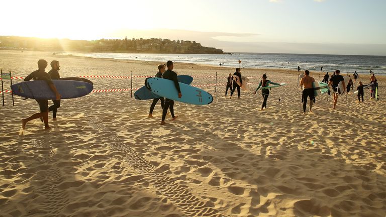 Les surfeurs se dirigent vers la plage alors que le verrouillage est assoupli