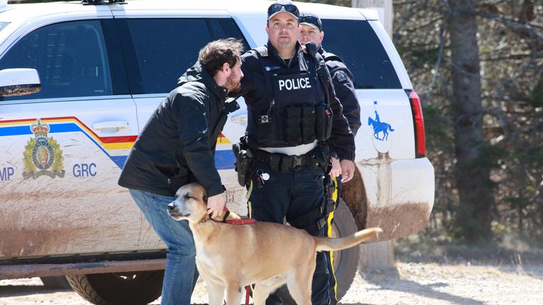 L'agent de la GRC, Cedric Landry, remet un chien à un homme au point de contrôle sur le chemin Portapique Beach après que Gabriel Wortman, un tireur présumé, a été arrêté à Portapique, en Nouvelle-Écosse, au Canada, le 19 avril 2020
