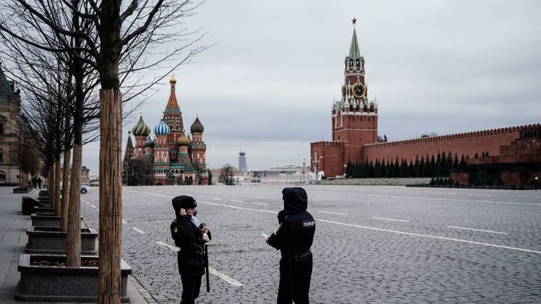 Des agents de police portant des masques faciaux patrouillent sur la place Rouge vide, avec la cathédrale Saint-Basile (L) et la tour Spasskaya du Kremlin (R) en arrière-plan, à Moscou le 30 mars 2020, au cours d'une verrouillage de la ville pour arrêter la propagation de l'épidémie COVID-19, causée par le nouveau coronavirus. - Moscou et sa région environnante ont imposé des blocages le 30 mars 2020, qui étaient suivis par d'autres régions russes dans le but de ralentir la propagation du coronavirus. L'application des nouvelles règles strictes,