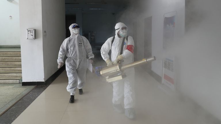Des volontaires en tenue de protection désinfectent un complexe résidentiel à Wuhan