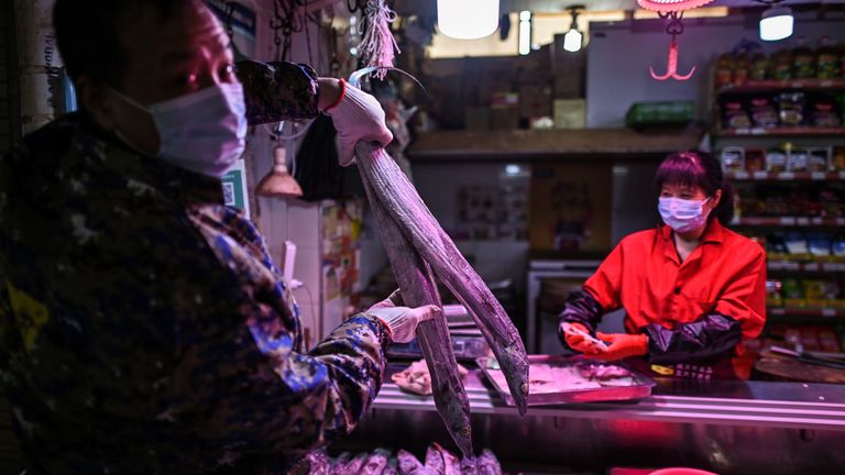 Un homme portant un masque facial tient un poisson dans un marché de Wuhan, dans la province centrale du Hubei, en Chine, le 7 avril 2020. - Wuhan, la ville du centre de la Chine où le coronavirus a fait son apparition l'année dernière, a en partie rouvert le 28 mars après plus de deux mois d'isolement quasi total pour sa population de 11 millions d'habitants. (Photo par Hector RETAMAL / AFP) (Photo par HECTOR RETAMAL / AFP via Getty Images)
