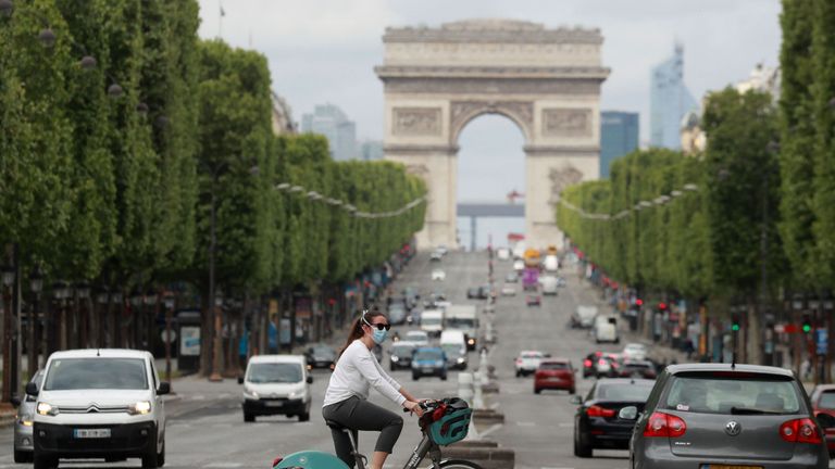 Un cycliste porte un masque facial en traversant l'avenue des Champs-Élysées à Paris le 4 mai 2020, le quarante-neuvième jour d'une interdiction stricte en France, en place pour tenter d'arrêter la propagation du nouveau coronavirus (COVID-19) . (Photo de Ludovic MARIN / AFP) (Photo de LUDOVIC MARIN / AFP via Getty Images)