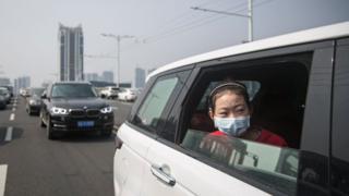 Une fille est assise dans la voiture pendant que la circulation s'arrête pendant un hommage silencieux à ceux qui sont morts du coronavirus à Wuhan.