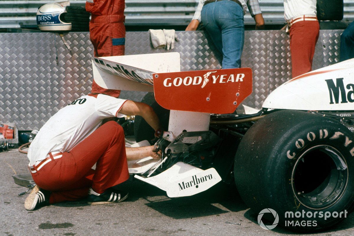 Un mécanicien travaille à l'arrière de la voiture de Jochen Mass, McLaren M23 Ford