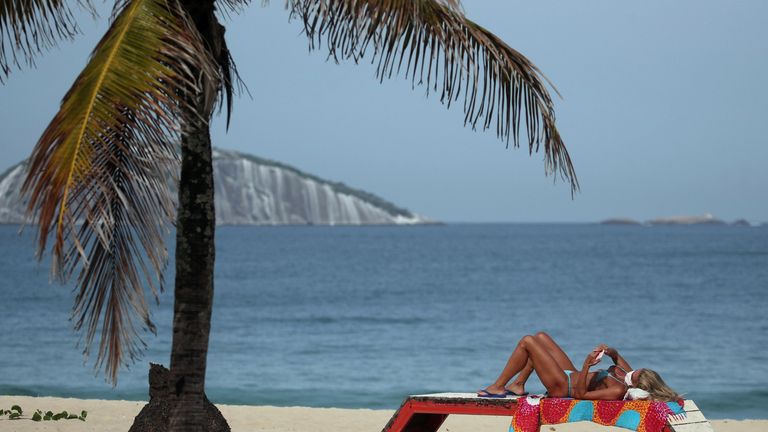Une femme portant un masque protecteur prend un bain de soleil sur la plage d'Ipanema au milieu de l'épidémie de coronavirus à Rio de Janeiro