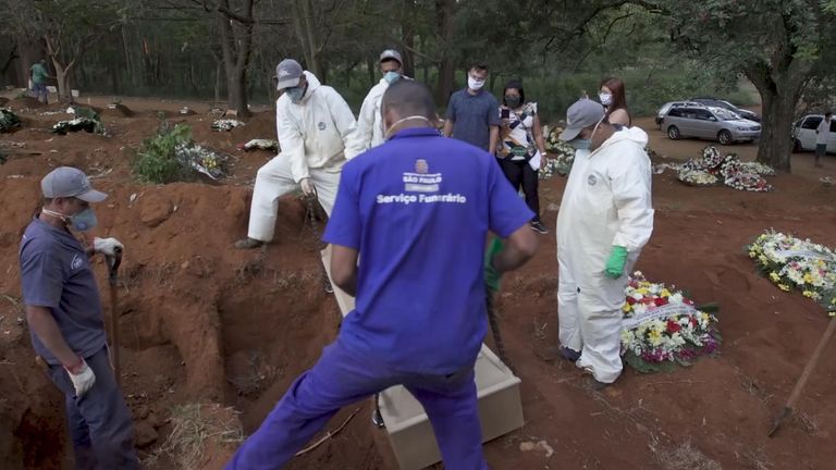 Les ouvriers du cimetière abaissent un cercueil dans une tombe
