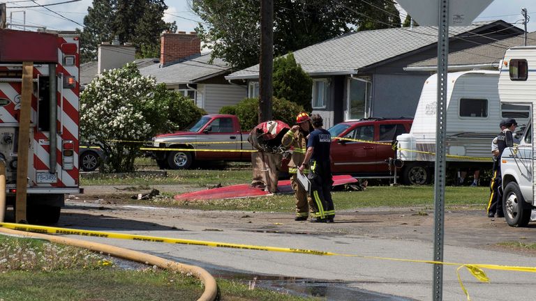 Des responsables des incendies discutent dans une rue résidentielle du quartier devant l'épave de la queue d'un jet des Snowbirds de l'Aviation royale canadienne après qu'un membre de l'équipe d'exposition s'est écrasé peu de temps après le décollage à Kamloops, Colombie-Britannique, Canada, le 17 mai 2020. REUTERS / Dennis Owen