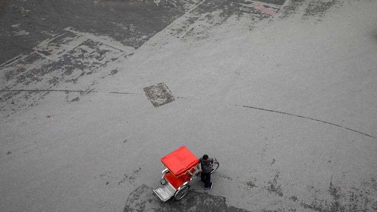 Un chauffeur de vélo à trois roues attend des clients sur une place vide au bord du lac Hoan Kiem dans le centre de Hanoi, Vietnam le 17 mars 2020. REUTERS / Kham
