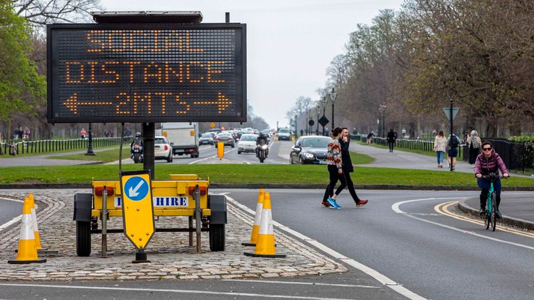 Un panneau informe les passants des mesures de distance sociale de 2 mètres en place, alors que les gens s'exercent dans le Phoenix Park à Dublin, le 25 mars 2020, après que l'Irlande a introduit des mesures pour aider à ralentir la propagation du nouveau coronavirus