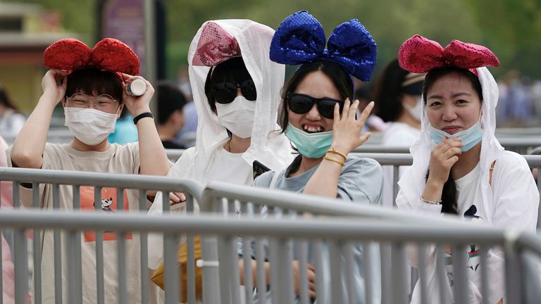 Des visiteurs portant des masques font la queue pour entrer dans le parc