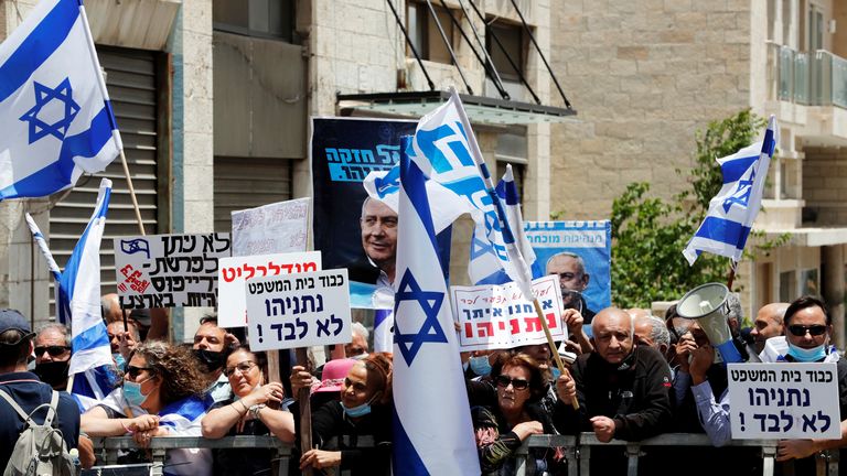 Les partisans du Premier ministre israélien Benjamin Netanyahu agitent des drapeaux israéliens et tiennent des pancartes alors qu'ils se rassemblent juste avant l'ouverture du procès pour corruption de Netanyahu, devant le tribunal de district de Jérusalem le 24 mai 2020. REUTERS / Ronen Zvulun