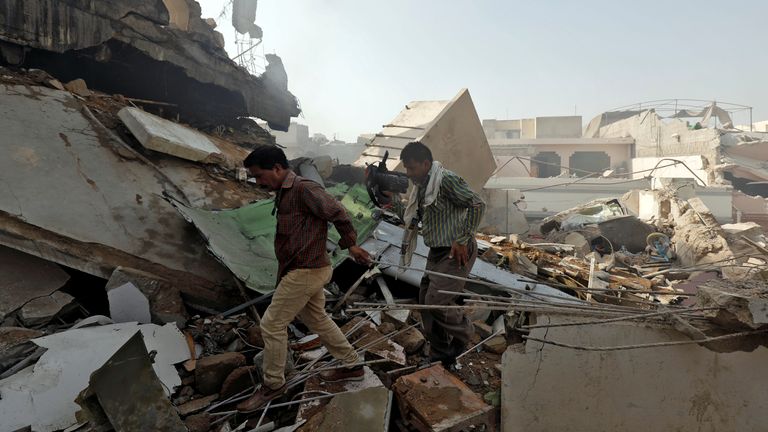 Des hommes marchent sur les débris sur le site d'un accident d'avion de passagers dans un quartier résidentiel près d'un aéroport à Karachi, au Pakistan, le 22 mai 2020. REUTERS / Akhtar Soomro