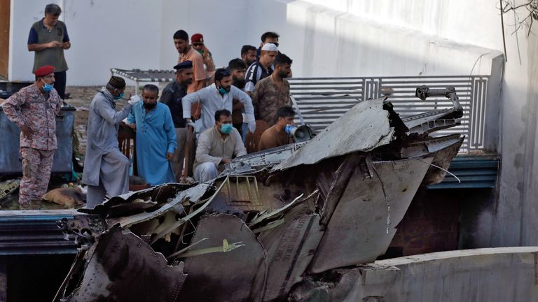 Des gens se tiennent à côté des débris d'un avion après s'être écrasé dans un quartier résidentiel près d'un aéroport à Karachi, au Pakistan, le 22 mai 2020. REUTERS / Akhtar Soomro