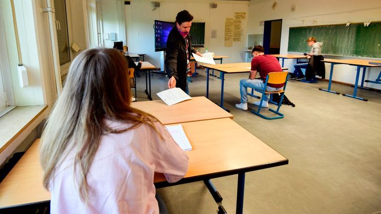 Un enseignant parle à quelques élèves qui se préparent socialement à distance dans leur école de Dortmund