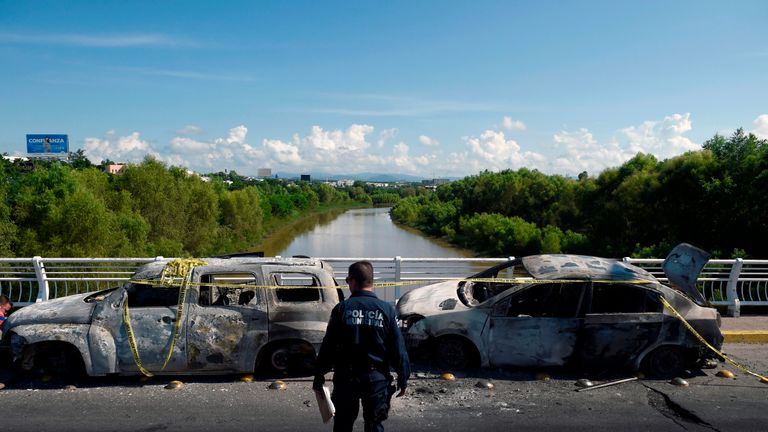 Un policier se tient à côté de véhicules incendiés après que des hommes armés lourdement armés ont mené une bataille sans merci contre les forces de sécurité mexicaines à Culiacan, dans l'État de Sinaloa, au Mexique, le 18 octobre 2019. - Le président du Mexique a fait face à une tempête de critiques vendredi alors que ses forces de sécurité confirmaient qu'elles a arrêté le cheville ouvrière du fils de Joaquin 