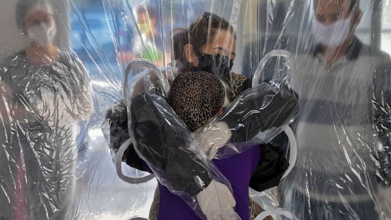 Une femme embrasse sa belle-sœur âgée à travers un rideau en plastique dans une maison de soins infirmiers à Sao Paulo, Brésil