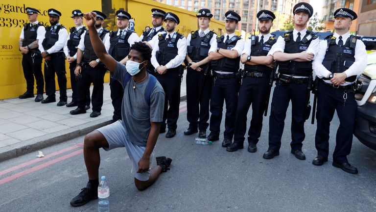 Un homme portant un masque protecteur s'agenouille devant des policiers près de l'ambassade des États-Unis à Londres, lors des manifestations de George Floyd
