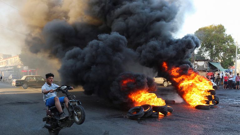 Un jeune conduit sa moto près de pneus en feu lors d'une manifestation contre la chute de la livre sterling et les difficultés économiques croissantes, à Ghazieh