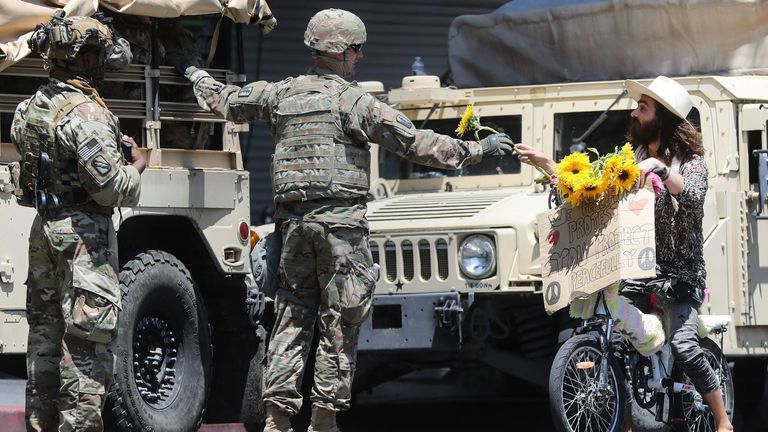 Un manifestant tend une fleur à un soldat de la Garde nationale lors d'une manifestation pacifique sur la mort de George Floyd à Hollywood