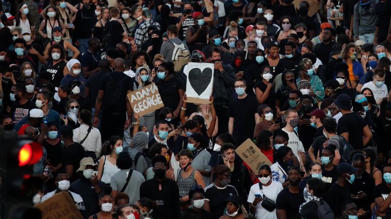 Un manifestant est vu avec une pancarte disant: & # 39; Adama George & # 39; 