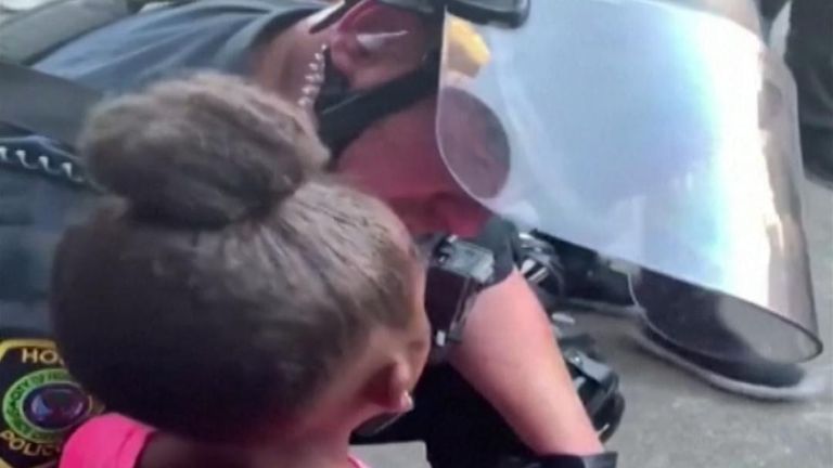 Un policier américain embrasse une fille qui pleure en lui demandant 