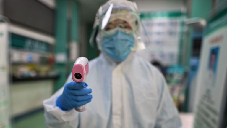 Un travailleur médical se prépare à vérifier la température de quelqu'un à Wuhan