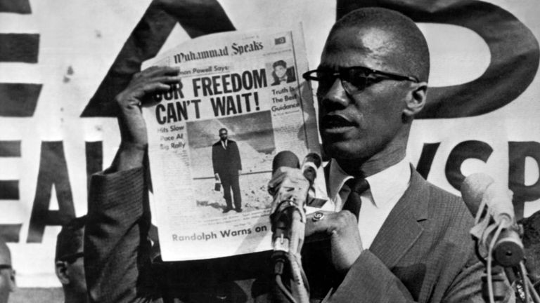 Malcolm X brandit un journal lors d'un rassemblement à New York en 1963