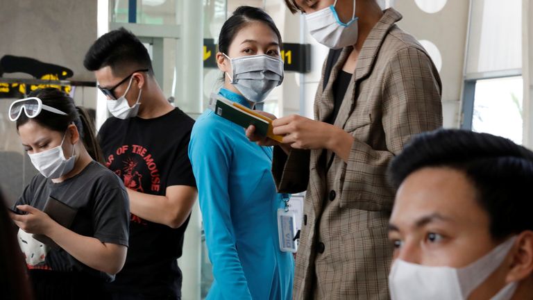 Un travailleur et des passagers de Vietnam Airlines portent des masques de protection à l'aéroport de Danang