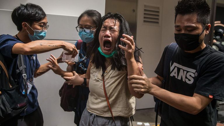 TOPSHOT - Une femme réagit après avoir été frappée avec du gaz poivré déployé par la police alors qu'elle nettoyait une rue avec des manifestants se rassemblant contre une nouvelle loi sur la sécurité nationale à Hong Kong le 1er juillet 2020, à l'occasion du 23e anniversaire du transfert de la ville de la Grande-Bretagne à la Chine .  - Un homme trouvé en possession d'un drapeau indépendantiste de Hong Kong est devenu la première personne à être arrêtée en vertu de la nouvelle loi de Pékin sur la sécurité nationale pour la ville, a annoncé la police le 1er juillet. (Photo DALE DE LA REY / AFP) (Photo DALE DE LA RE