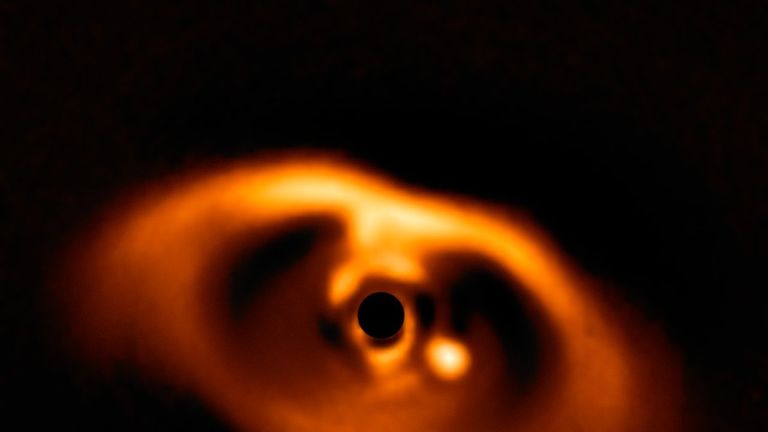 Cette image spectaculaire de l'instrument SPHERE sur le Very Large Telescope de l'ESO est la première image claire d'une planète prise dans l'acte même de formation autour de l'étoile naine PDS 70. La planète se détache clairement, visible comme un point lumineux à droite de la centre de l'image, qui est noirci par le masque de coronographe utilisé pour bloquer la lumière aveuglante de l'étoile centrale.  Crédit: ESO / A.  Müller et coll.