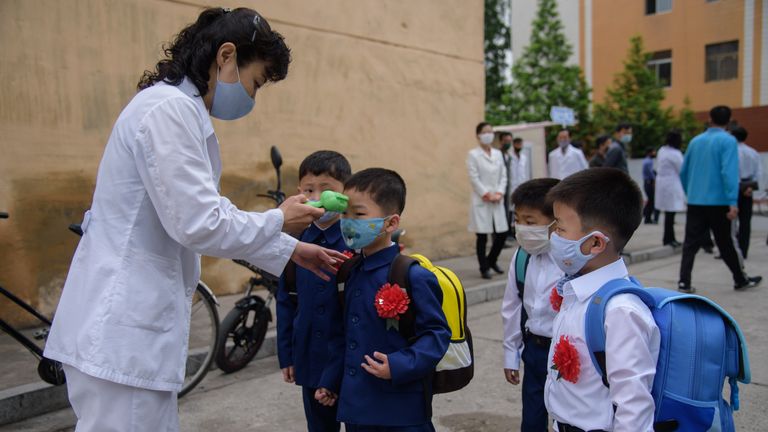 Des enfants de l'école primaire portant des masques faciaux alors qu'ils font contrôler leur température en Corée du Nord