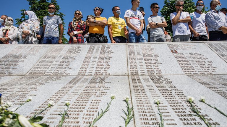 Les personnes en deuil au mémorial regardent la liste des noms de ceux qui ont été tués