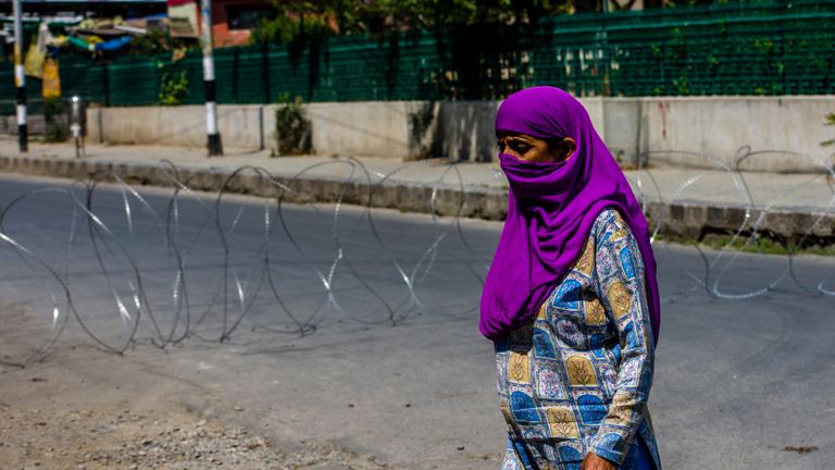 SRINAGAR, KASHMIR - INDE - 05 août: une femme musulmane du Cachemire marche devant un fil de rasoir concertina des forces du gouvernement indien fermant une route dans le centre-ville désert pendant un couvre-feu comme des restrictions, un an après que l'Inde a révoqué le statut spécial de Jammu et Cachemire, dans le centre-ville le 05 août 2020 à Srinagar, la capitale d'été du Cachemire indien, en Inde.  La police indienne et le personnel paramilitaire ont été déployés en force alors que les autorités imposaient des restrictions de type couvre-feu dans la capitale d'été Srinagar à l'occasion du premier anniversaire du gouvernement indien qui a dépouillé la région himalayenne, contestée par l'Inde et le Pakistan depuis 1947, de son autonomie et de la rétrogradation de son statut. d'un état à un territoire de l'union dans un mouvement furtif l'année dernière.  La région est déjà sous le choc d'un verrouillage imposé par les autorités pour freiner la propagation du coronavirus.  (Photo par Yawar Nazir / Getty Images)