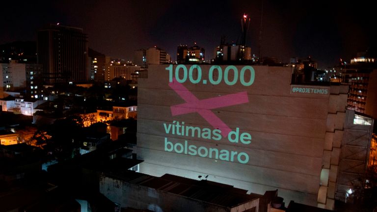 TOPSHOT - Une projection sur un bâtiment honorant les 100000 victimes décédées du nouveau coronavirus COVID-19 au Brésil lit 