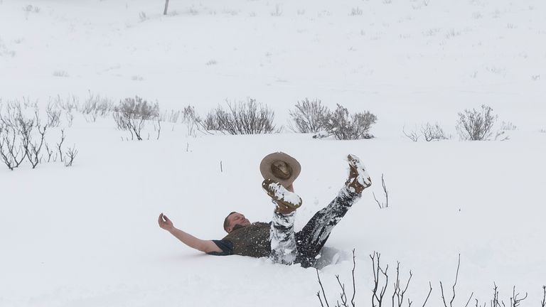 Le touriste Barry Mckowski, qui voit de la neige pour la première fois, s'enfonce dans la neige le 23 août 2020 près de la petite ville des Snowy Mountains d'Adaminaby, en Australie