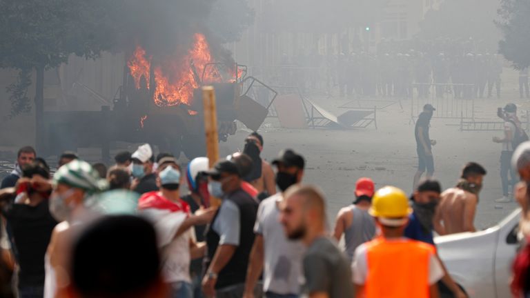 Un véhicule brûle alors que des manifestants tentent de franchir une barrière près du bâtiment du parlement