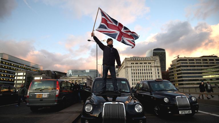 Un chauffeur de taxi noir agite un drapeau Union Jack en se tenant debout sur un taxi sur le pont de Londres, lors d'une manifestation contre TfL et Uber